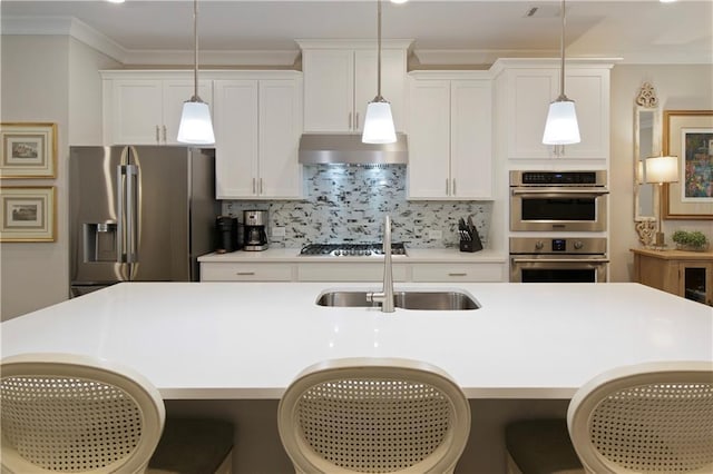 kitchen with a center island with sink, ornamental molding, stainless steel appliances, a sink, and exhaust hood