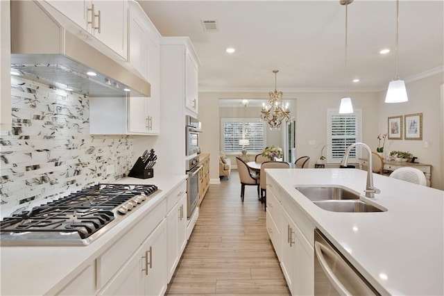 kitchen with light countertops, decorative backsplash, appliances with stainless steel finishes, a sink, and under cabinet range hood