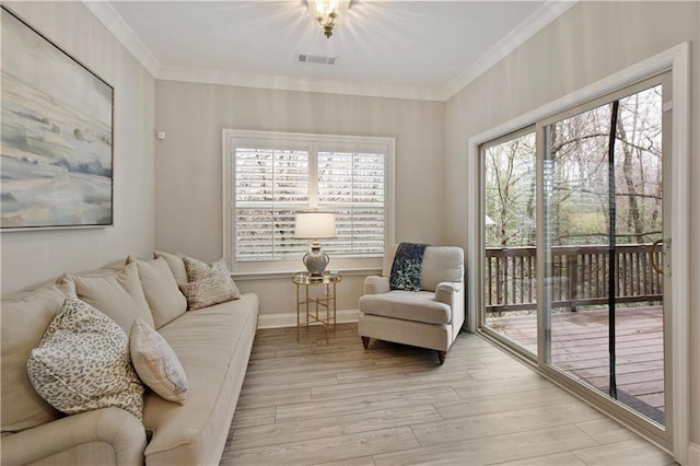 living room featuring baseboards, visible vents, crown molding, and light wood finished floors