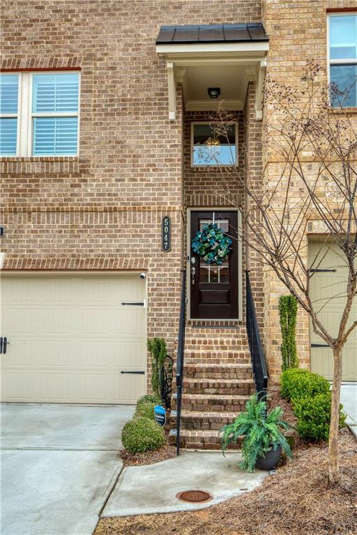 entrance to property featuring a garage, driveway, and brick siding