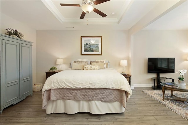 bedroom featuring a raised ceiling, visible vents, light wood-style flooring, ceiling fan, and baseboards