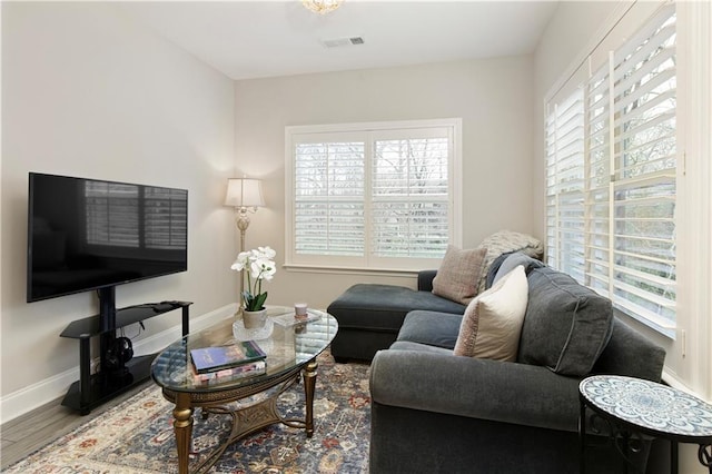 living area with baseboards, visible vents, a wealth of natural light, and wood finished floors