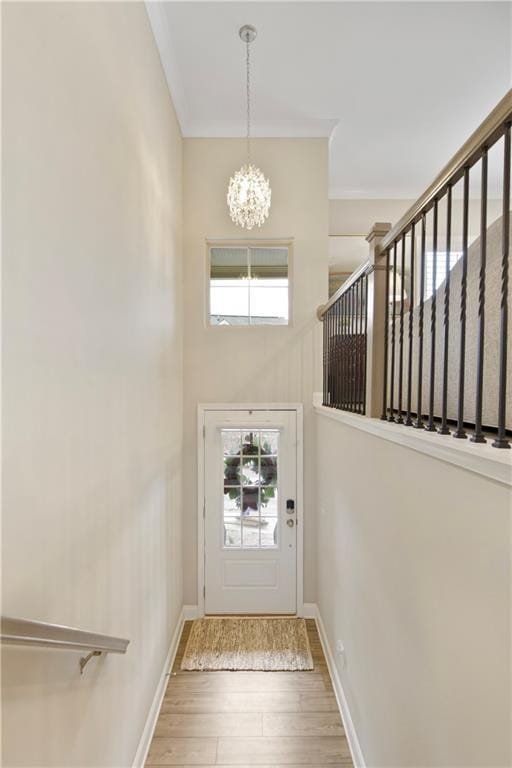 foyer with wood finished floors, baseboards, stairway, an inviting chandelier, and crown molding