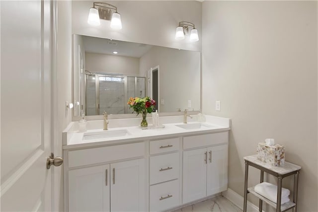 full bath with marble finish floor, double vanity, a stall shower, and a sink