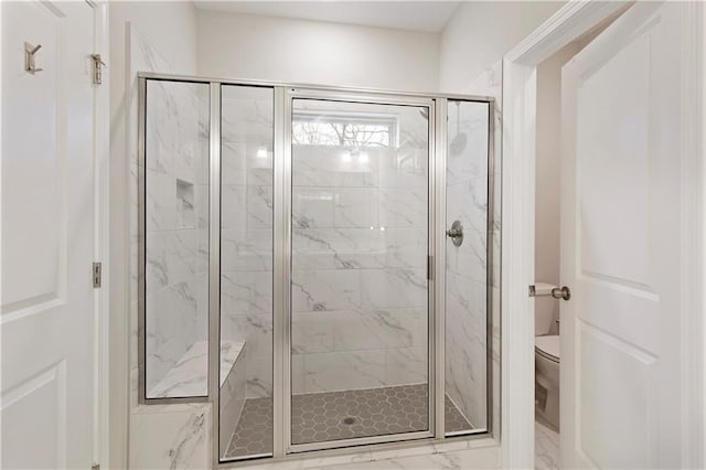 full bathroom with toilet and a marble finish shower