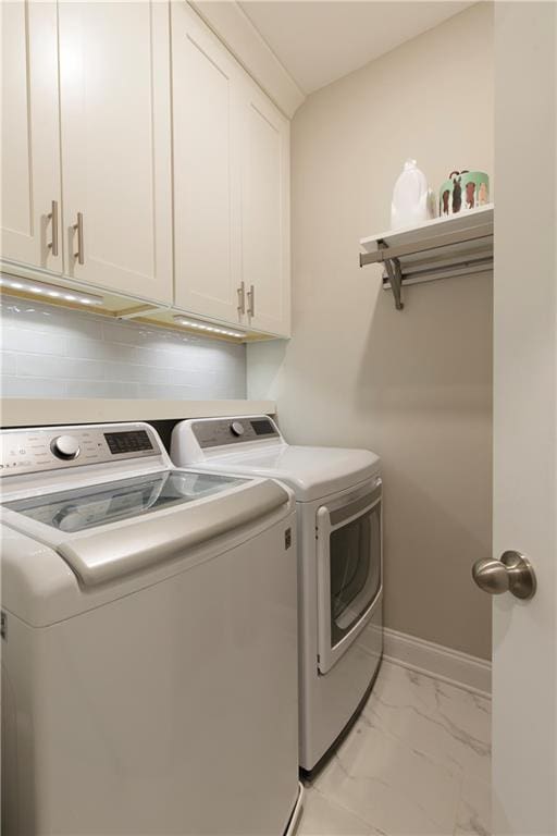 laundry room featuring baseboards, marble finish floor, cabinet space, and washer and dryer