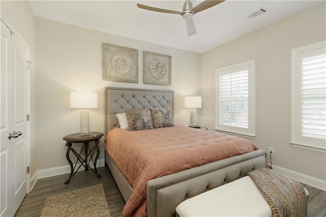 bedroom featuring baseboards, multiple windows, visible vents, and wood finished floors