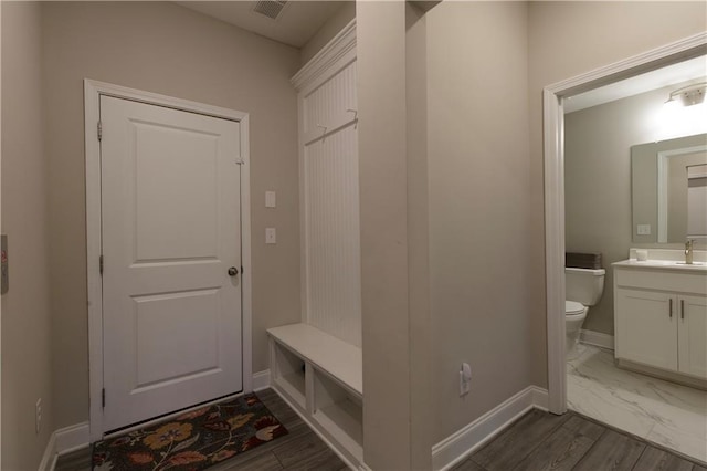 mudroom featuring baseboards, visible vents, and a sink