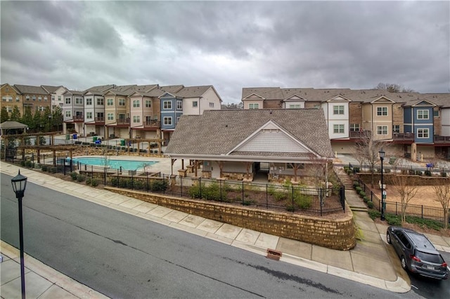 view of front of house featuring a residential view, a community pool, and fence private yard