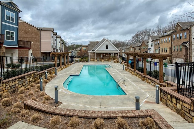 pool with a patio area, a residential view, and fence