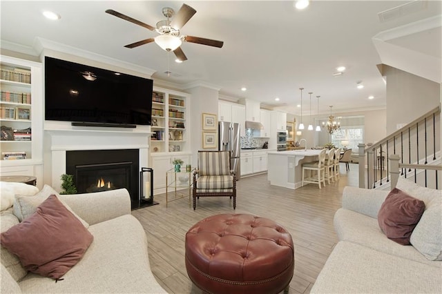 living room with ornamental molding, light wood-type flooring, a warm lit fireplace, and recessed lighting