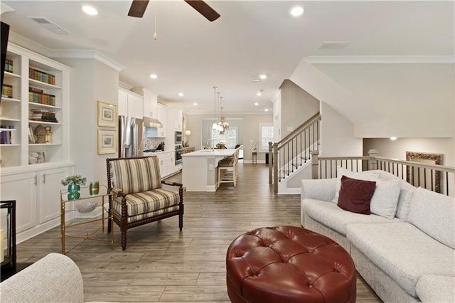 living room featuring recessed lighting, ceiling fan with notable chandelier, wood finished floors, visible vents, and crown molding