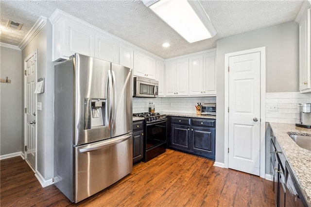 8450 Jot Em Down Rd, Gainesville, GA 30506 - kitchen featuring light stone countertops, a textured ceiling, dark wood-type flooring, white cabinets, and appliances with stainless steel finishes