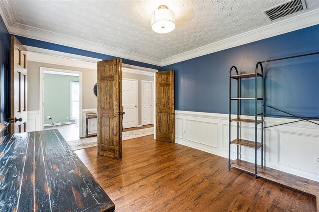8450 Jot Em Down Rd, Gainesville, GA 30506 - unfurnished bedroom featuring wood finished floors, ornamental molding, a textured ceiling, visible vents, and wainscoting