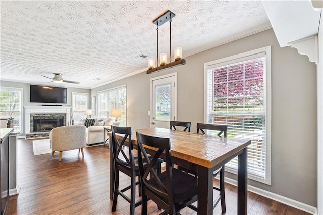 8450 Jot Em Down Rd, Gainesville, GA 30506 - dining room with dark wood-style flooring, ornamental molding, a stone fireplace, and a ceiling fan