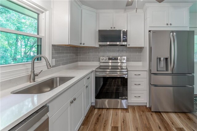 3620 W Lawrenceville St, Duluth, GA 30096 - kitchen featuring stainless steel appliances, white cabinets, light wood-type flooring, and backsplash