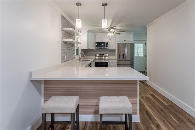 3620 W Lawrenceville St, Duluth, GA 30096 - kitchen featuring appliances with stainless steel finishes, a peninsula, light countertops, decorative backsplash, and crown molding