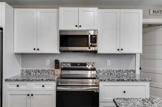 kitchen featuring stainless steel appliances, white cabinetry, and light stone countertops