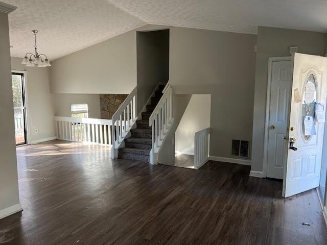 spare room featuring dark hardwood / wood-style flooring, lofted ceiling, a textured ceiling, and an inviting chandelier