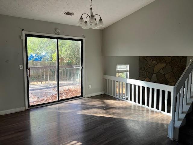 unfurnished living room featuring dark hardwood / wood-style flooring, a textured ceiling, and a chandelier