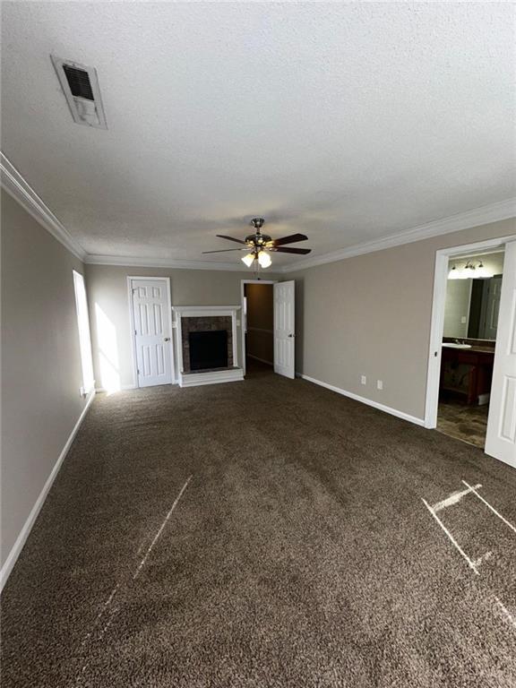 unfurnished living room featuring crown molding, a textured ceiling, and dark colored carpet