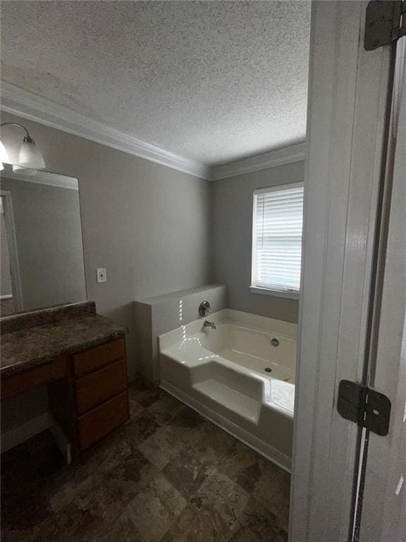 bathroom featuring vanity, ornamental molding, a tub, and a textured ceiling