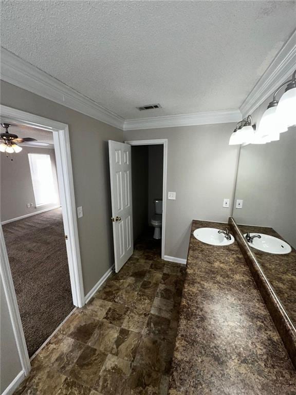 bathroom featuring toilet, crown molding, a textured ceiling, vanity, and ceiling fan