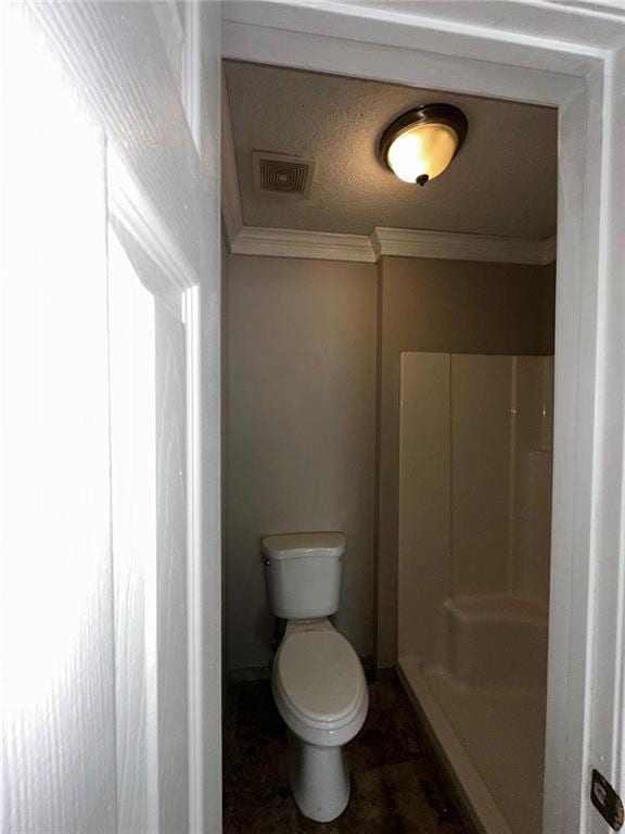 bathroom featuring ornamental molding, toilet, a textured ceiling, and a shower