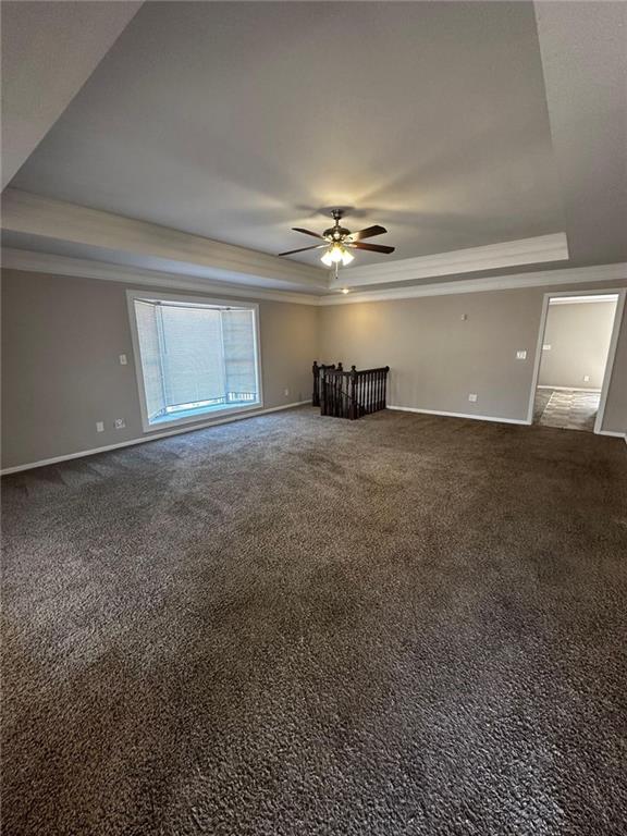 unfurnished living room featuring carpet floors, a raised ceiling, and ceiling fan