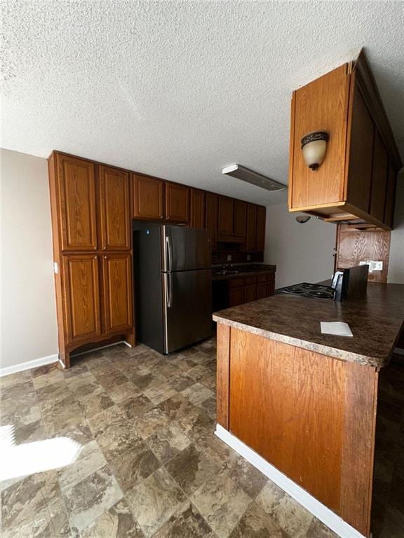 kitchen with stainless steel fridge, kitchen peninsula, and a textured ceiling