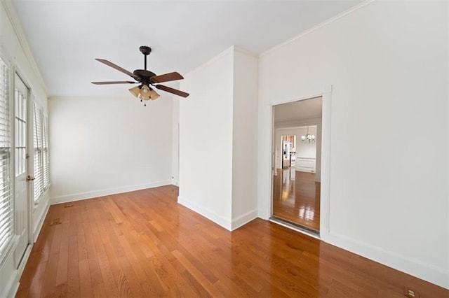 unfurnished room with hardwood / wood-style flooring, ornamental molding, and ceiling fan with notable chandelier