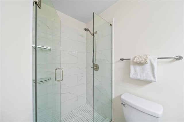 bathroom featuring toilet and a shower with door