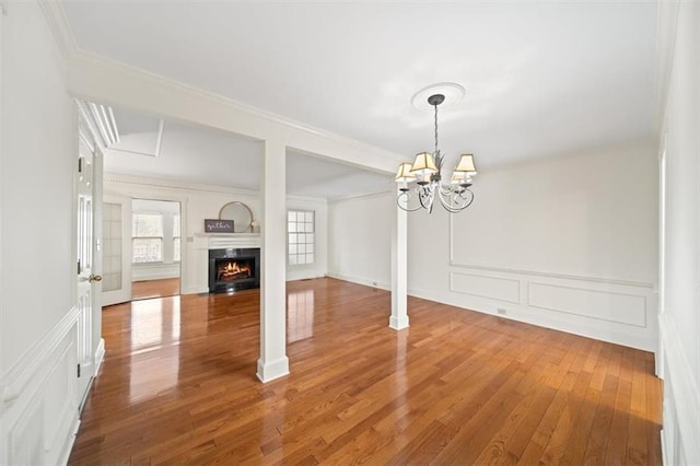 unfurnished dining area featuring ornamental molding, wood-type flooring, and a chandelier