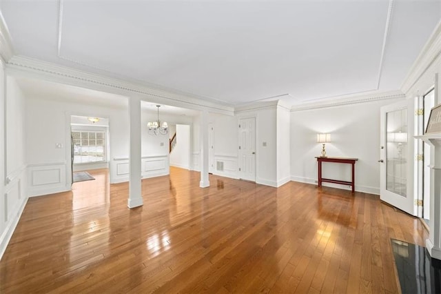 unfurnished living room with wood-type flooring, ornamental molding, and an inviting chandelier