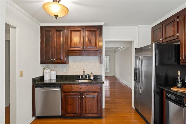 kitchen featuring sink, crown molding, light hardwood / wood-style flooring, stainless steel appliances, and tasteful backsplash