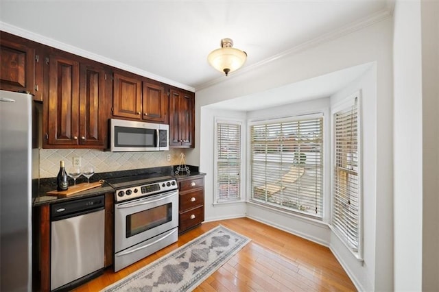 kitchen with appliances with stainless steel finishes, backsplash, dark brown cabinetry, ornamental molding, and light hardwood / wood-style floors