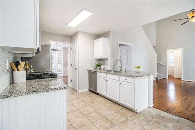 3710 Ridgefair Dr, Cumming, GA 30040 - kitchen featuring stainless steel dishwasher, light tile patterned floors, tasteful backsplash, white cabinetry, and light stone counters