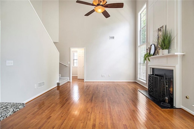 3710 Ridgefair Dr, Cumming, GA 30040 - unfurnished living room featuring stairway, a high ceiling, hardwood / wood-style floors, a ceiling fan, and a fireplace with raised hearth