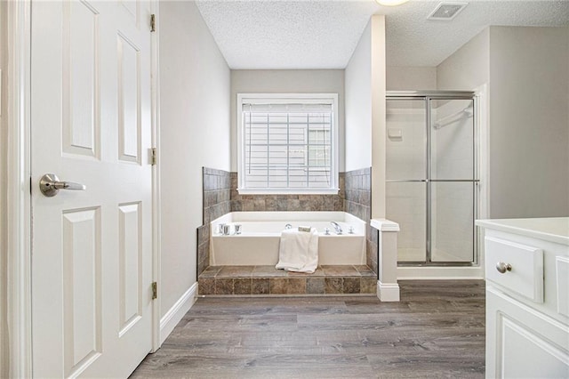 3710 Ridgefair Dr, Cumming, GA 30040 - bathroom with wood finished floors, a stall shower, a bath, vanity, and a textured ceiling