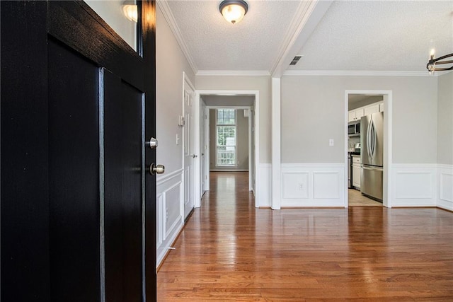 3710 Ridgefair Dr, Cumming, GA 30040 - entrance foyer with light wood-type flooring, ornamental molding, a textured ceiling, wainscoting, and a chandelier