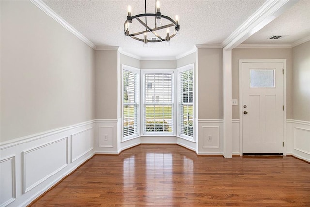 3710 Ridgefair Dr, Cumming, GA 30040 - entryway featuring a chandelier, wood finished floors, a decorative wall, a textured ceiling, and wainscoting