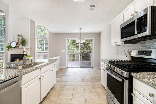 3710 Ridgefair Dr, Cumming, GA 30040 - kitchen featuring stainless steel appliances, backsplash, white cabinetry, light stone counters, and a textured ceiling