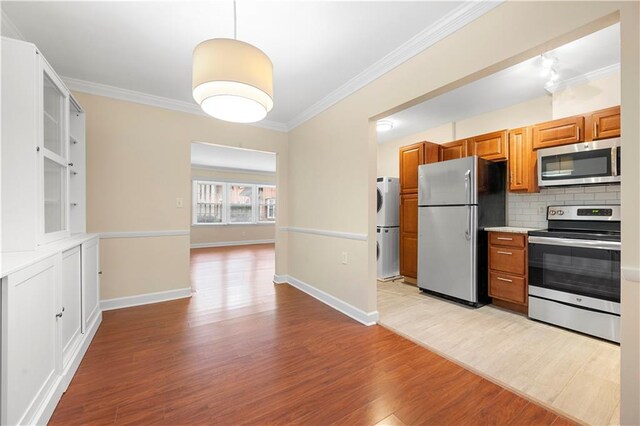 kitchen featuring stainless steel appliances, tasteful backsplash, stacked washer / drying machine, and light stone counters