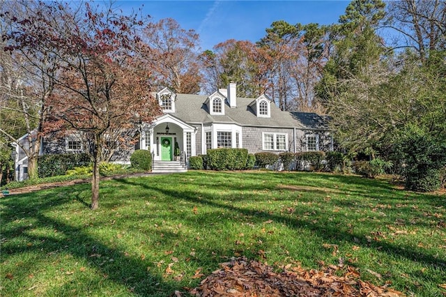 cape cod-style house with a chimney and a front yard