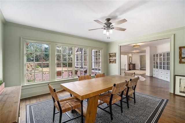 dining area featuring dark wood finished floors, a ceiling fan, baseboards, and ornamental molding