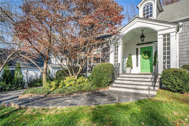 entrance to property featuring roof with shingles