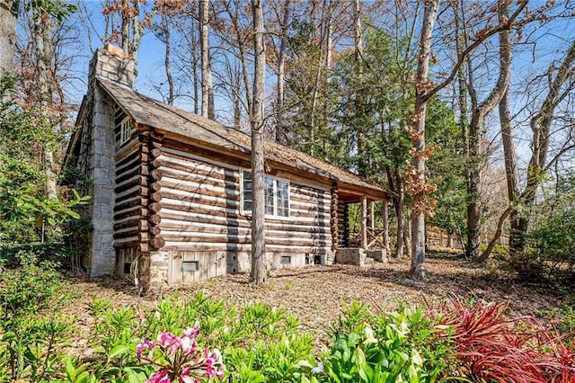 view of home's exterior featuring log siding, crawl space, and a chimney