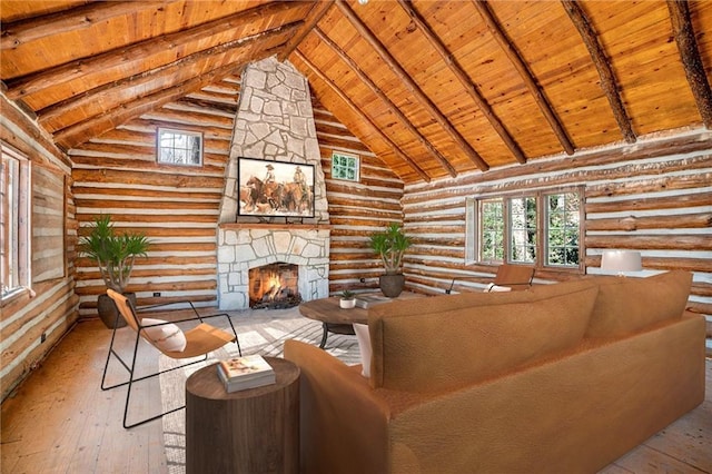 living room featuring beamed ceiling, high vaulted ceiling, wood-type flooring, a stone fireplace, and wooden ceiling