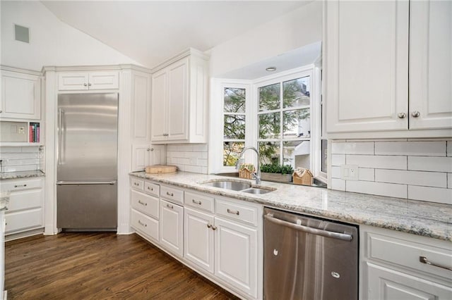 kitchen featuring vaulted ceiling, white cabinets, stainless steel appliances, and a sink