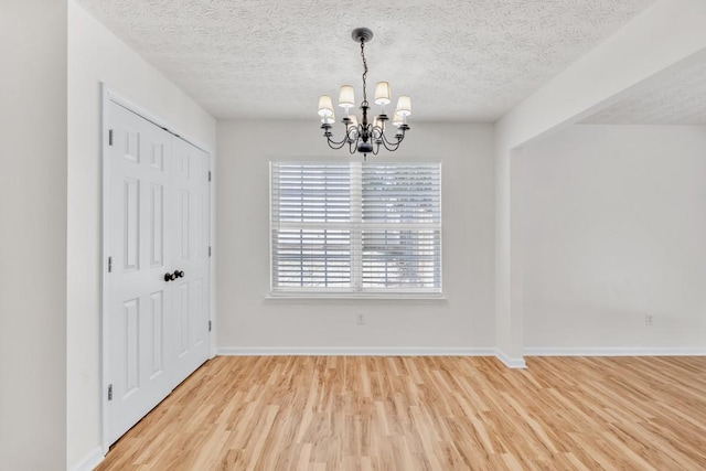 1186 Hawthorn Ln, Grayson, GA 30017 - unfurnished dining area featuring a chandelier, light wood-type flooring, a textured ceiling, and baseboards